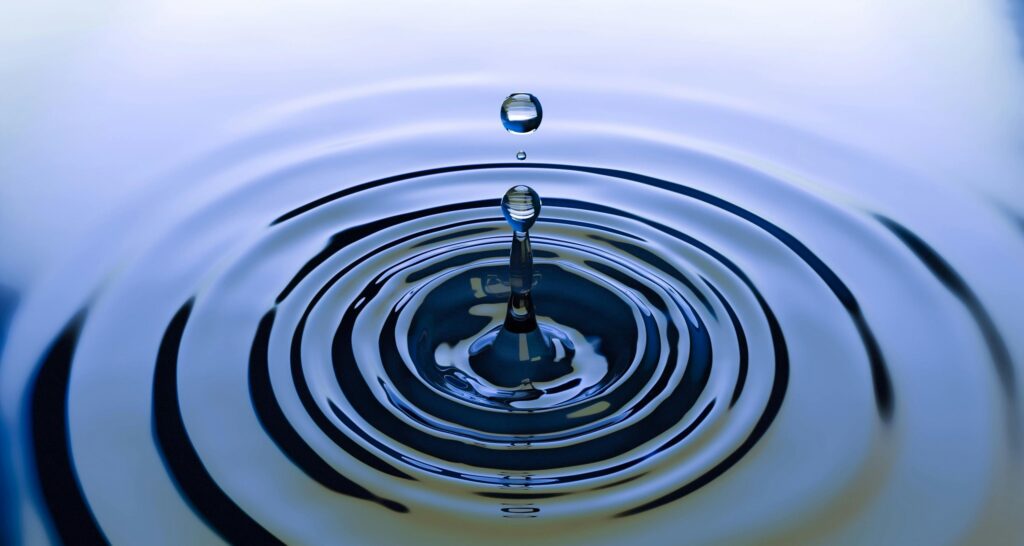 pexels-photo-220213-220213 A stunning close-up of a water droplet creating ripples on a smooth water surface, capturing nature's simplicity.